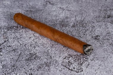 Tütün yapraklarından yapılmış bir puro gri mermer bir masanın üzerinde yatıyor. Yüksek kalite fotoğraf