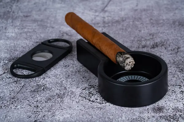 Masanın üzerindeki kül tablasında yanan bir puro yatıyor. Yüksek kalite fotoğraf