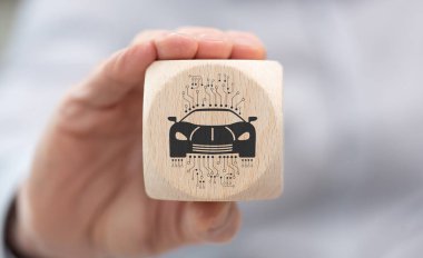 Elinde akıllı araba konseptinin sembolü olan tahta bir küp var.