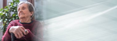 Yaşlı kadın elleri değneğin üzerinde oturuyor; panoramik pankart