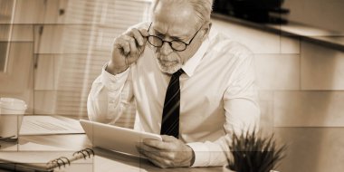 İş yerinde dijital tablet kullanan kıdemli işadamı, geometrik desen