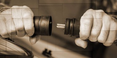 Electrician hands holding electrical plugs, geometric pattern