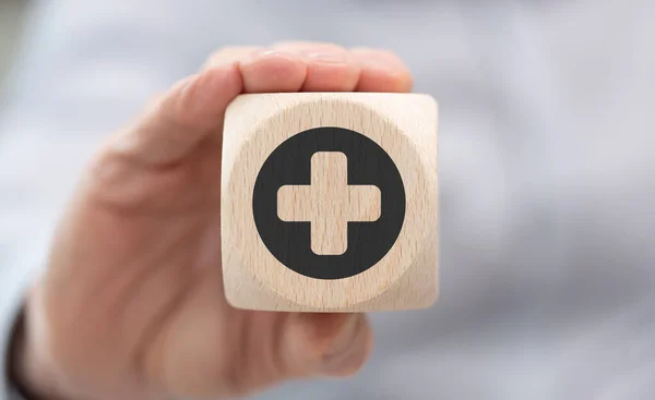 ヘルスケアの概念の象徴と木製のキューブを保持手 — ストック写真