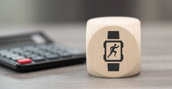 Wooden block with symbol of wearable technology concept and calculator on background