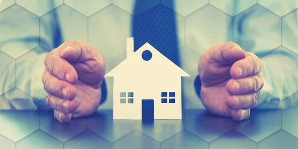 Stock image Insurer protecting a house with his hands, color effect, geometric pattern