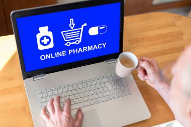 Ekranda online eczane konsepti olan bir dizüstü bilgisayar kullanan adam.
