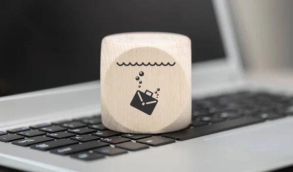 Wooden block with symbol of job loss concept on laptop keyboard