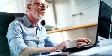 Ofiste dizüstü bilgisayarda çalışan kıdemli işadamının portresi, sert ışık, geometrik desen