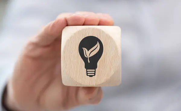 Hand holding a wooden cube with symbol of green energy concept