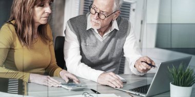 Ofiste dizüstü bilgisayarda çalışan iki olgun iş arkadaşı, geometrik desen