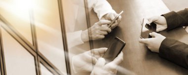 Group of people using and looking at mobile phone together; multiple exposure