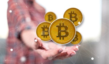 Bitcoin kavramı arka plandaki bir kadının elinin üstünde.