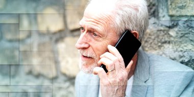 Olgun adam cep telefonunu açık havada kullanıyor, geometrik desenli.