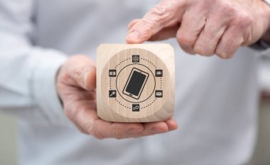Hand holding a wooden cube with symbol of mobile apps concept