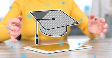 Arka planda bir kadının elleri arasında mezuniyet konsepti olan dijital tablet