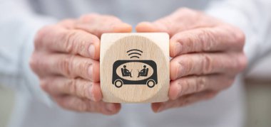 Hand holding a wooden cube with symbol of self-driving car concept