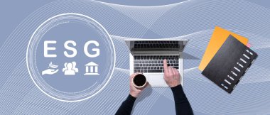 ESG kavramının sembolü olan dizüstü bilgisayar kullanan ellerin üst görünümü