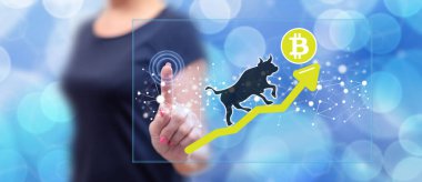 Dokunmatik ekranda parmaklarıyla bitcoin 'e dokunan bir kadın.