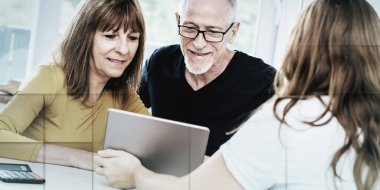 Emlakçı yaşlı çifte tablet üzerinde açıklama yapıyor, geometrik desenli.