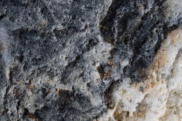 Texture of river stone, light gray in color with shiny minerals, close-up backdrop