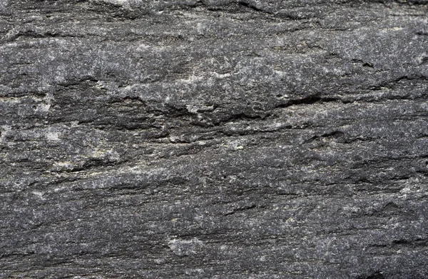 River stone texture, dark gray color with shiny minerals. close-up backdrop