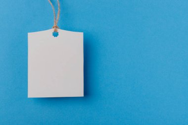 mavi arkaplanda bir ipte boş beyaz dikdörtgen kağıt etiket