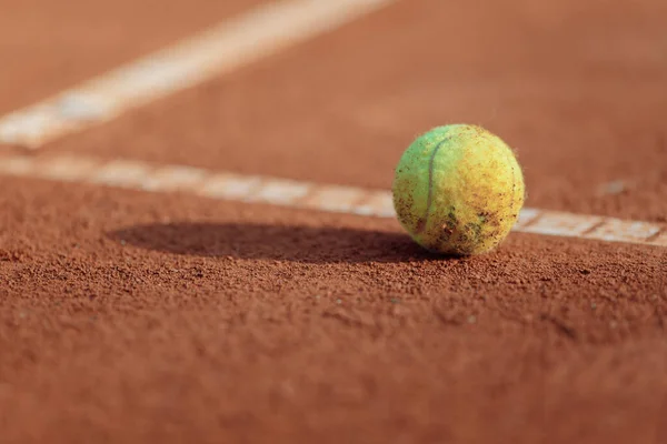 tennis ball on a clay court sun
