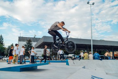 Kyiv, Ukrayna - 12 Eylül 2021: Ekstrem bisikletçi kaykay parkında numaralar yapıyor. Olağanüstü bir spor. Kalabalık bir kaykay parkı. Bir grup adam rampada numaralar yapıyor. BMX numaraları.