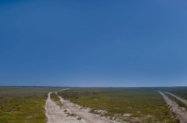 Dirt roads in the desert steppes, above them a huge blue sky.