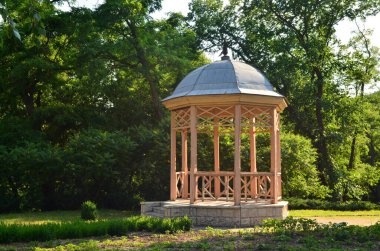 Orman yeşilliğinin arka planına karşı Antik çardak.