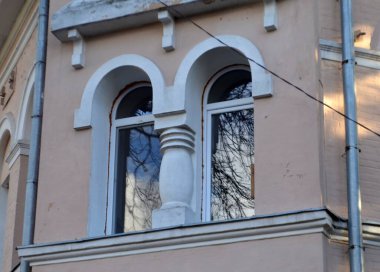 : Gökyüzü ve ağaçların yansıttığı eski bir evin penceresi.