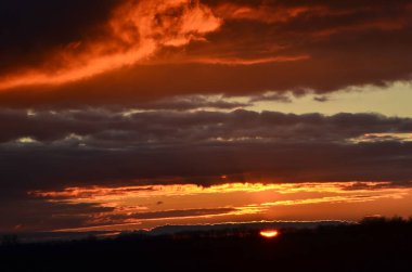 Günbatımı, altın, turuncu, kırmızı bulutlar, karanlık gökyüzüne karşı.