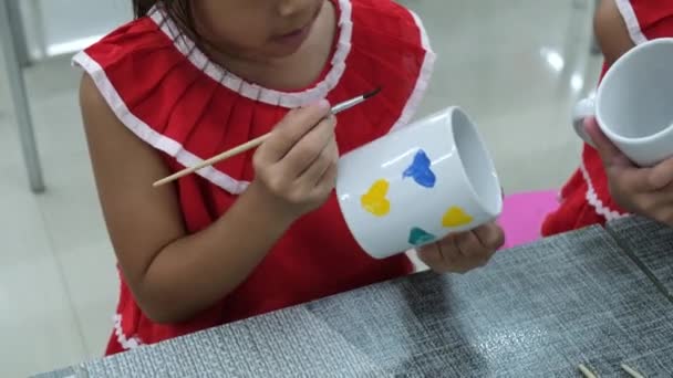 Nettes Kleines Mädchen Zeichnet Und Malt Auf Keramikbecher Mit Farben — Stockvideo