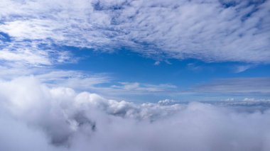 Sabahları bulutlu güzel gökyüzü manzarası. Mavi gökyüzünün üstündeki güneş parlayan bulutların havadan görünüşü. Dağın tepesindeki sis denizi manzarası. Gökyüzü doğa arkaplanı.