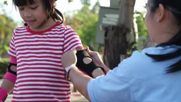 Νεαρή Μητέρα Βοηθάει Την Κόρη Της Βάλει Προστατευτικά Και Κράνος — Αρχείο Βίντεο