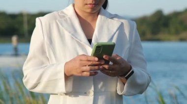 Environmental engineer wearing a white helmet uses a mobile phone to record data analyzing oxygen levels in a reservoir. Water and ecology concept.