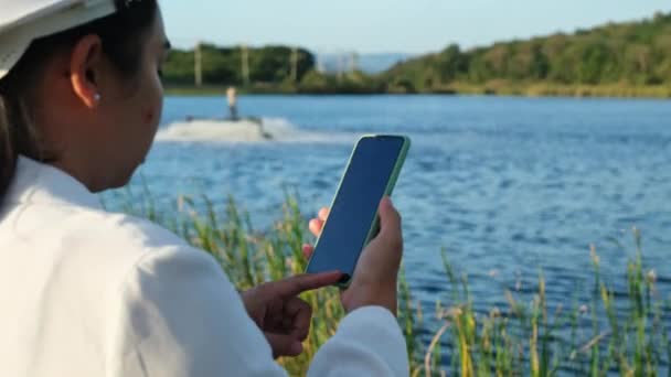 戴着白色头盔的环境工程师使用手机在池塘里操作氧气涡轮曝气机 水和生态概念 — 图库视频影像