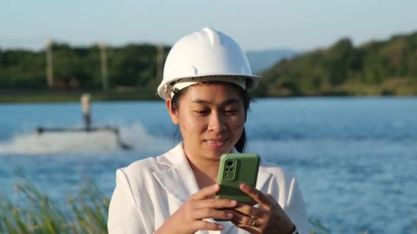 戴着白色头盔的环境工程师使用手机记录分析储气罐中氧气含量的数据 水和生态概念 — 图库视频影像