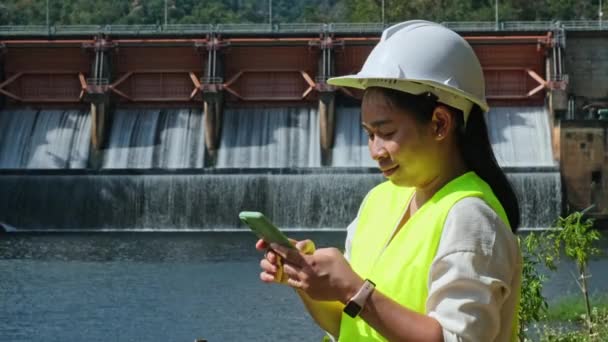Жінка Інженер Білому Капелюсі Працює Смартфоном Дивиться Греблю Гідроелектростанцією Зрошенням — стокове відео