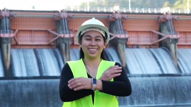 Усміхнена Жінка Інженер Зеленому Жилеті Шоломі Стоїть Зовні Тлі Гідроелектричної — стокове відео