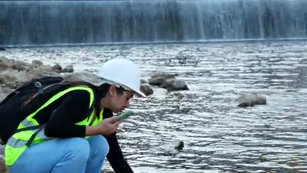 Женщина Эколог Использует Мобильный Телефон Записи Данных Анализа Воды Плотине — стоковое видео