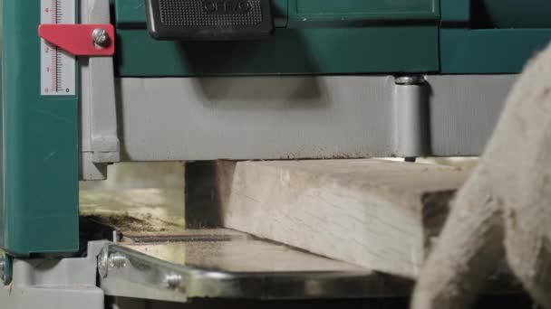 作業場で木工機械を扱う男性大工 産業用切断装置の中を飛んで木製のおがくずの多く 選択的フォーカスでクローズアップ撮影 大工道具 — ストック動画
