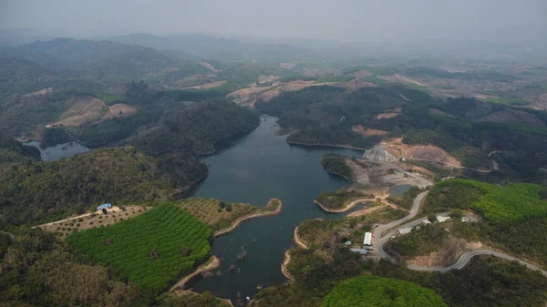 Water dam and lake reservoir panoramic aerial view on the hills of northern Thailand. Aerial view on mountain lake. Drone over water reservoir at mountain valley covered with green spring forest.