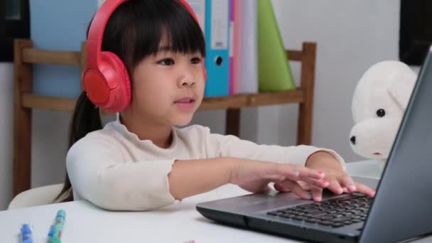 Menina Escola Primária Bonito Usando Fones Ouvido Usando Computador Portátil — Vídeo de Stock