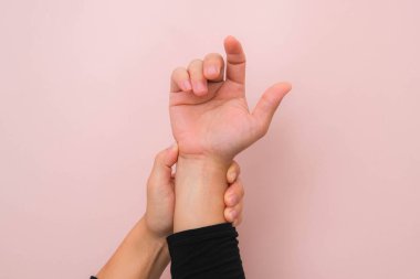 Pembe arka planda, acı veren bileğini eklem iltihabından ya da Karpal Tünel Sendromu 'ndan (CST) tutan kadının yakın çekimi. Sağlık hizmeti kavramı.