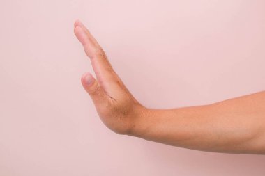 Yakın çekim erkek eli pembe arka planda izole edilmiş dur hareketi ile.