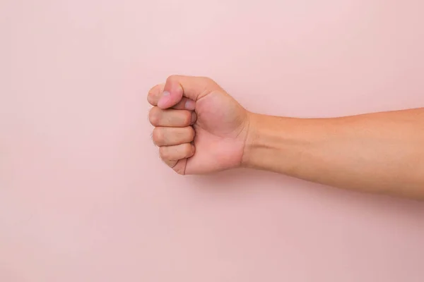 Male hand with fist gesture isolated on pink background. Male clenched fist.