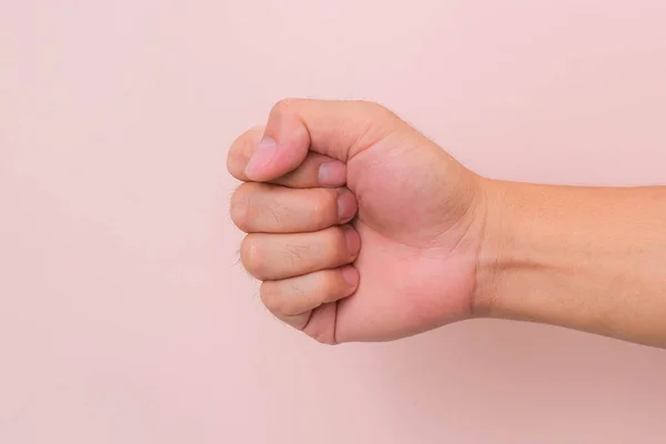 Male hand with fist gesture isolated on pink background. Male clenched fist.
