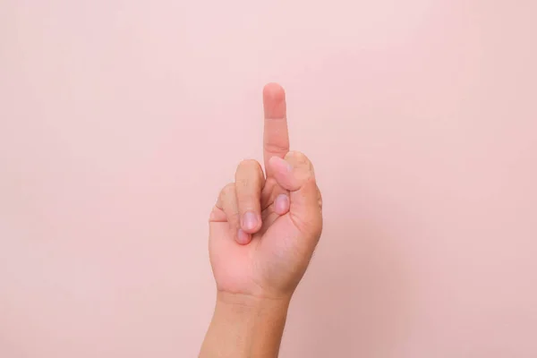 Hand showing middle finger gesture (fuck you sign) isolated on pink background.