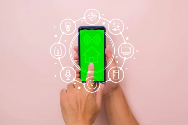 Akıllı telefon uygulaması ekranında akıllı ev teknolojisi arayüzü olan pembe arka planda akıllı telefonu tutan bir erkek. Otomasyon kavramı.